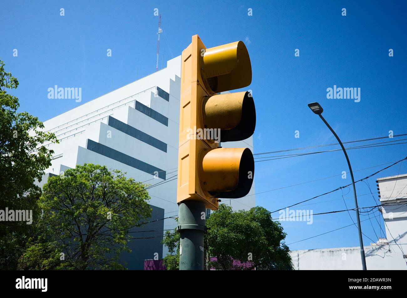 Gelbe Ampel in der Nähe von Gebäuden und blauer Himmel auf der Straße. Stockfoto