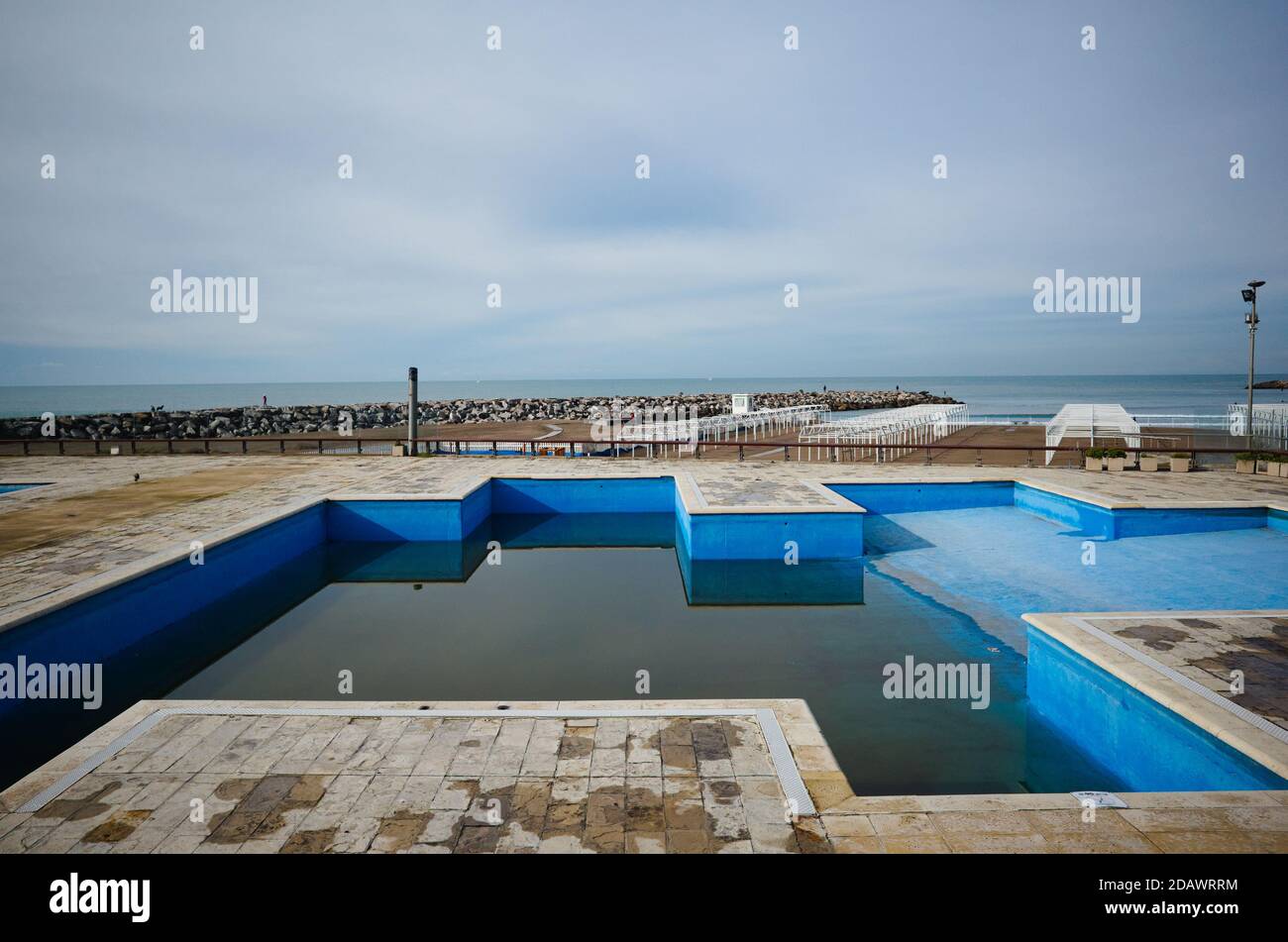 Halb gefüllter Swimmingpool mit schmutzigem Wasser am geschlossenen leeren Strand während der Quarantäne in Mar del Plata, Argentinien. Stockfoto