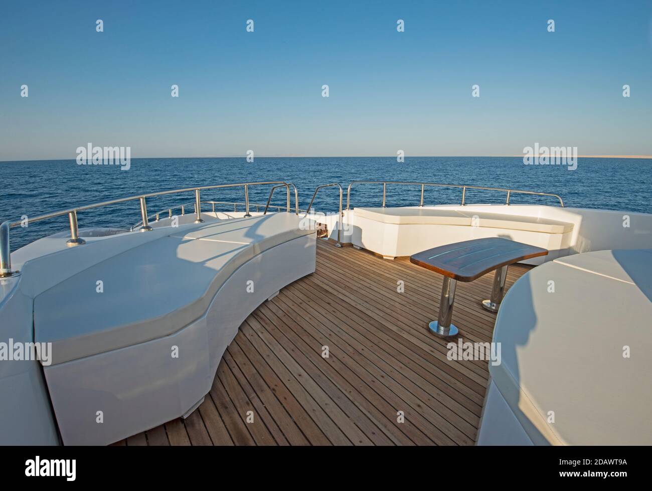 Teak Bugdeck einer großen Luxus-Motoryacht mit Stühle, Couchtisch und tropischer Meerblick im Hintergrund Stockfoto