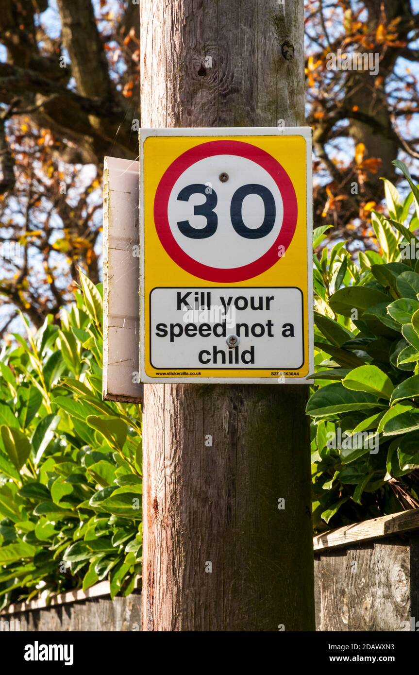 Straßenschild warnt vor 30 mph Geschwindigkeitsbegrenzung mit Schild mit der Aufschrift Kill your Speed not a child. Stockfoto