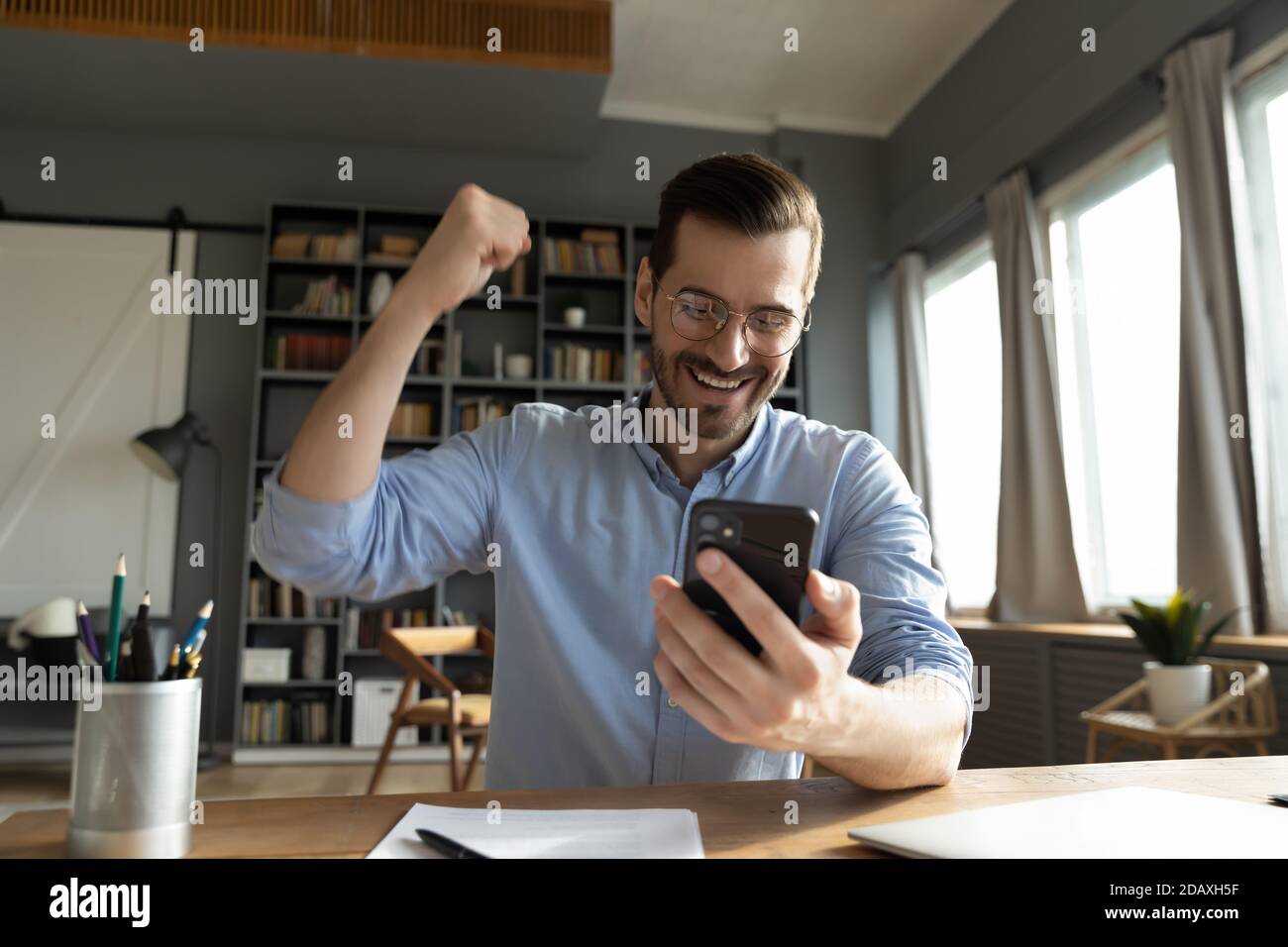 Der Mann, der auf den Bildschirm des Smartphones schaut, fühlt sich glücklich Stockfoto