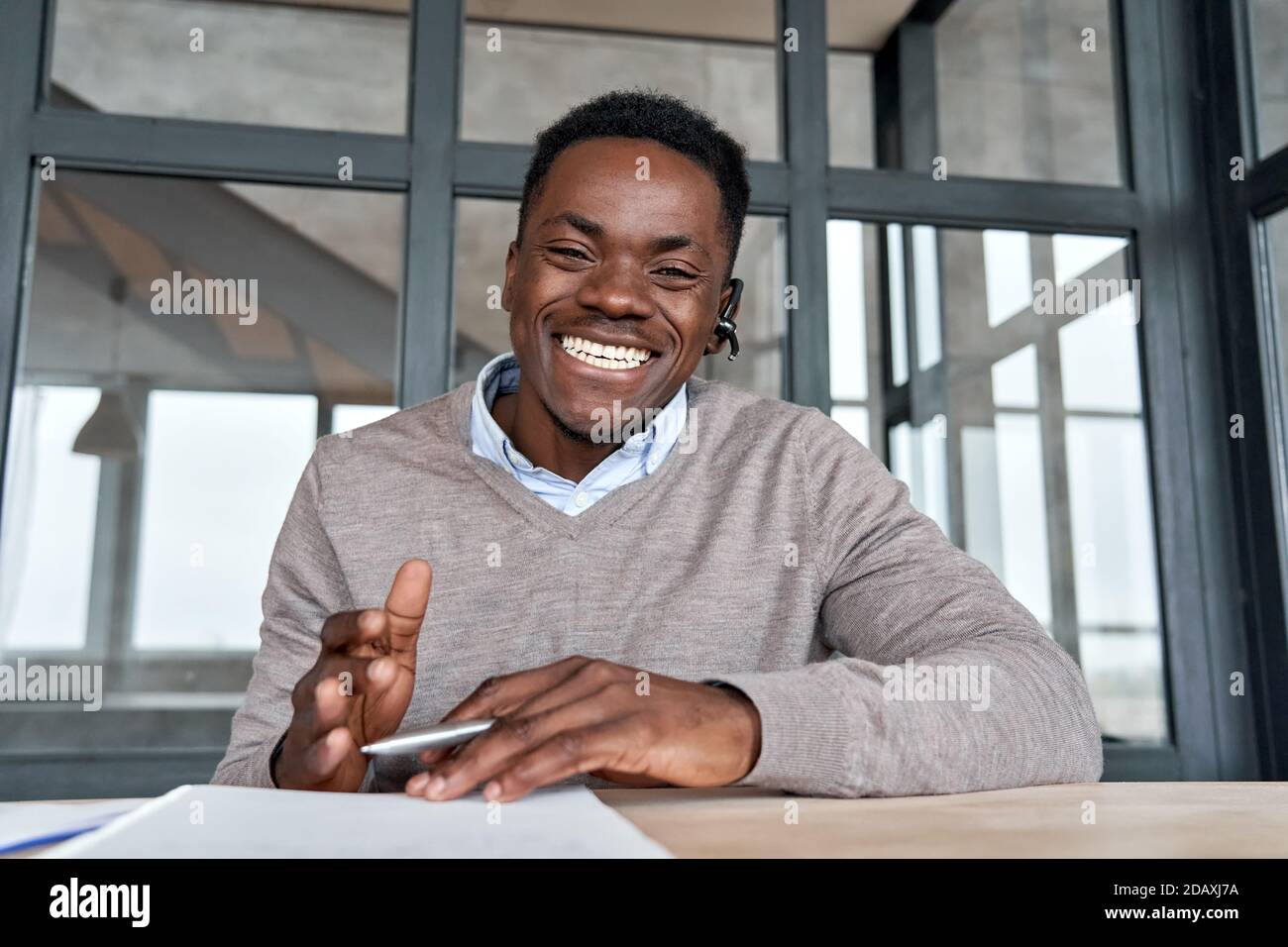 Fröhlicher afrikanischer Geschäftsmann im Gespräch mit Web-Cam während der Konferenz. Stockfoto