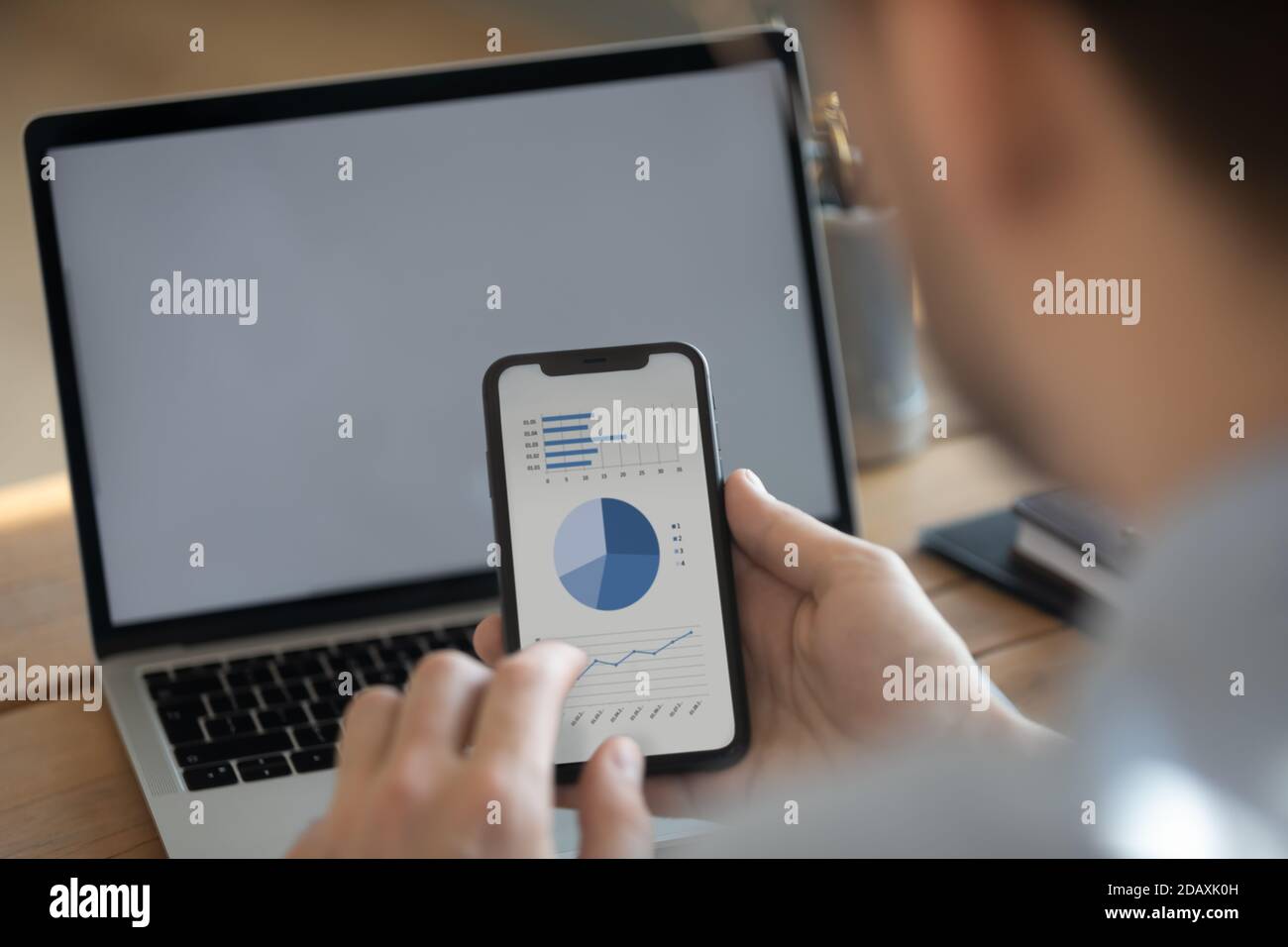 Geschäftsmann synchronisieren Informationen mit Laptop und Smartphone mit Finanzdaten Stockfoto