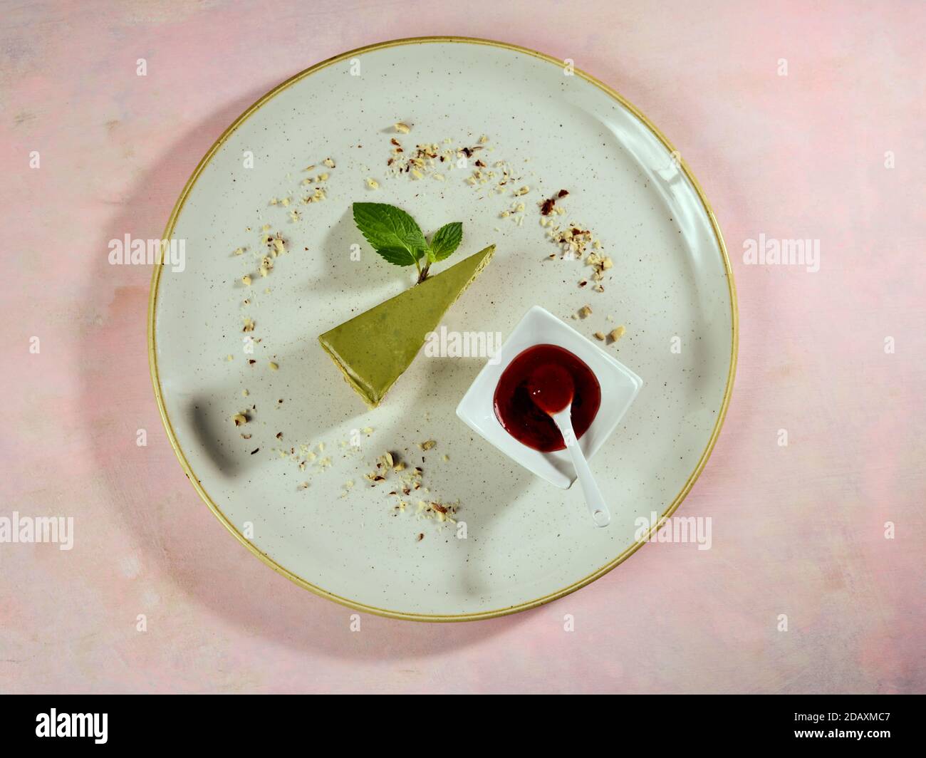 Scheibe Matcha Käsekuchen aus der Nähe, typische Fusion japanische Fusion Kuchen. Es kommt mit Himbeer-Muse und Blätter von frischer Minze als Garnierung. Stockfoto