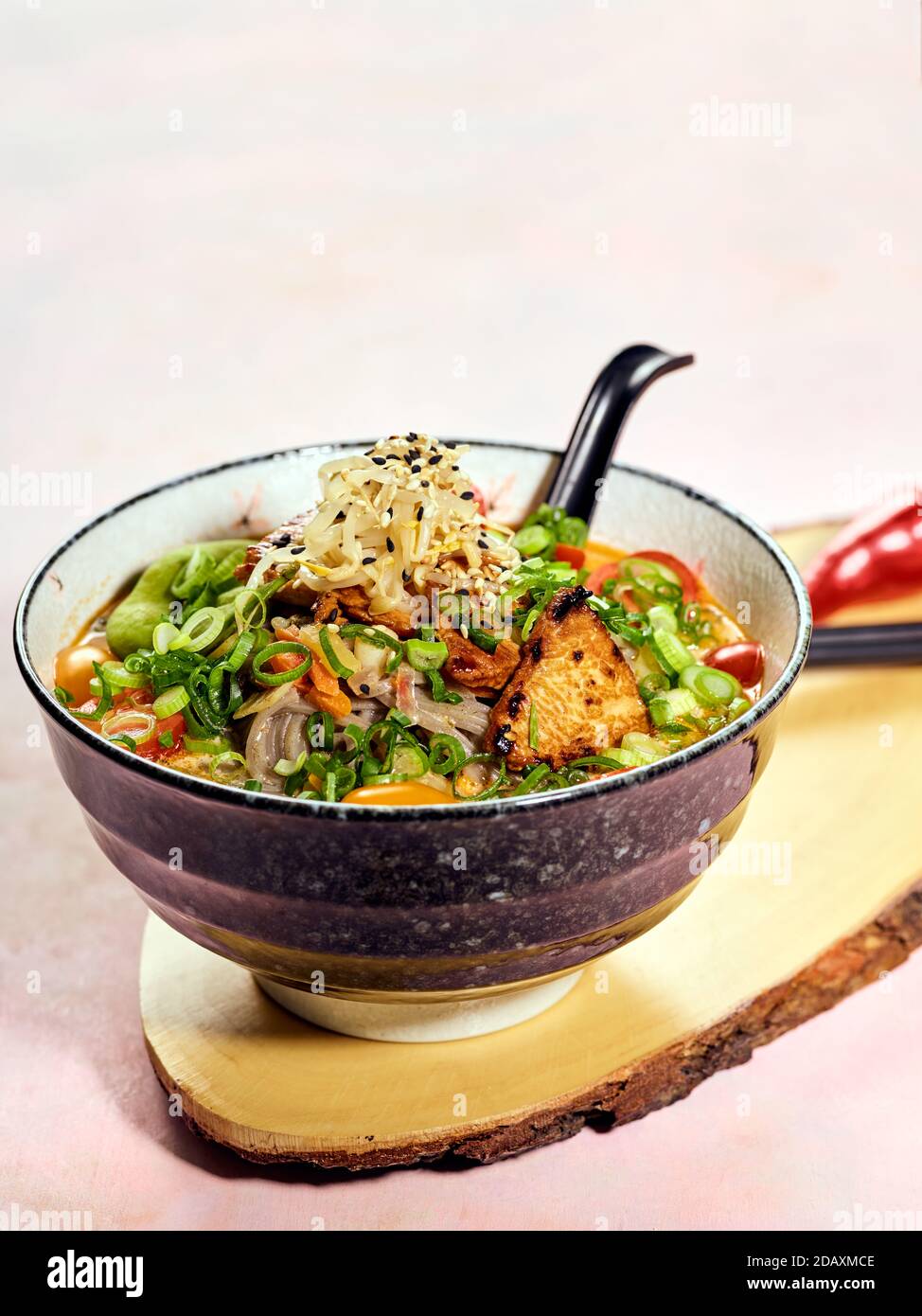 Schüssel mit japanischer Ramen-Suppe mit gebratenem Lachs mit dunklen Soba-Nudeln. Suppe aus schmackhaftem Fischbarsch mit Stücken gebratenem Lachs, Kirschtomaten, Lch Stockfoto