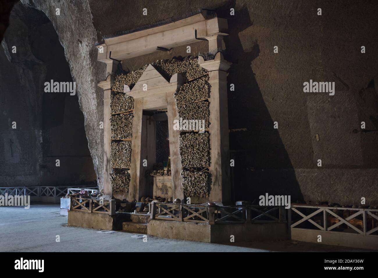 Seitenaltar aus gestapelten menschlichen Knochen im Friedhof Fontanelle (Cimitero delle Fontanelle) in Neapel, Kampanien, Italien. Das ehemalige Leichenhaus (Beinhaus) in einer Höhle im Stadtteil Materdei war der Ort, an dem sich in Neapel der spontane Kult der Hingabe an die Überreste namenlos Verstorbener entwickelte. Die Verteidiger des Kults besuchten die namenlosen Schädel im Beinhaus, um sie zu adoptieren und den Schädeln sogar Namen zu geben. Adoptierte Schädel wurden in der dekorierten Box platziert und wurden zum Gegenstand des regelmäßigen Gebets und Votivopfers. Stockfoto