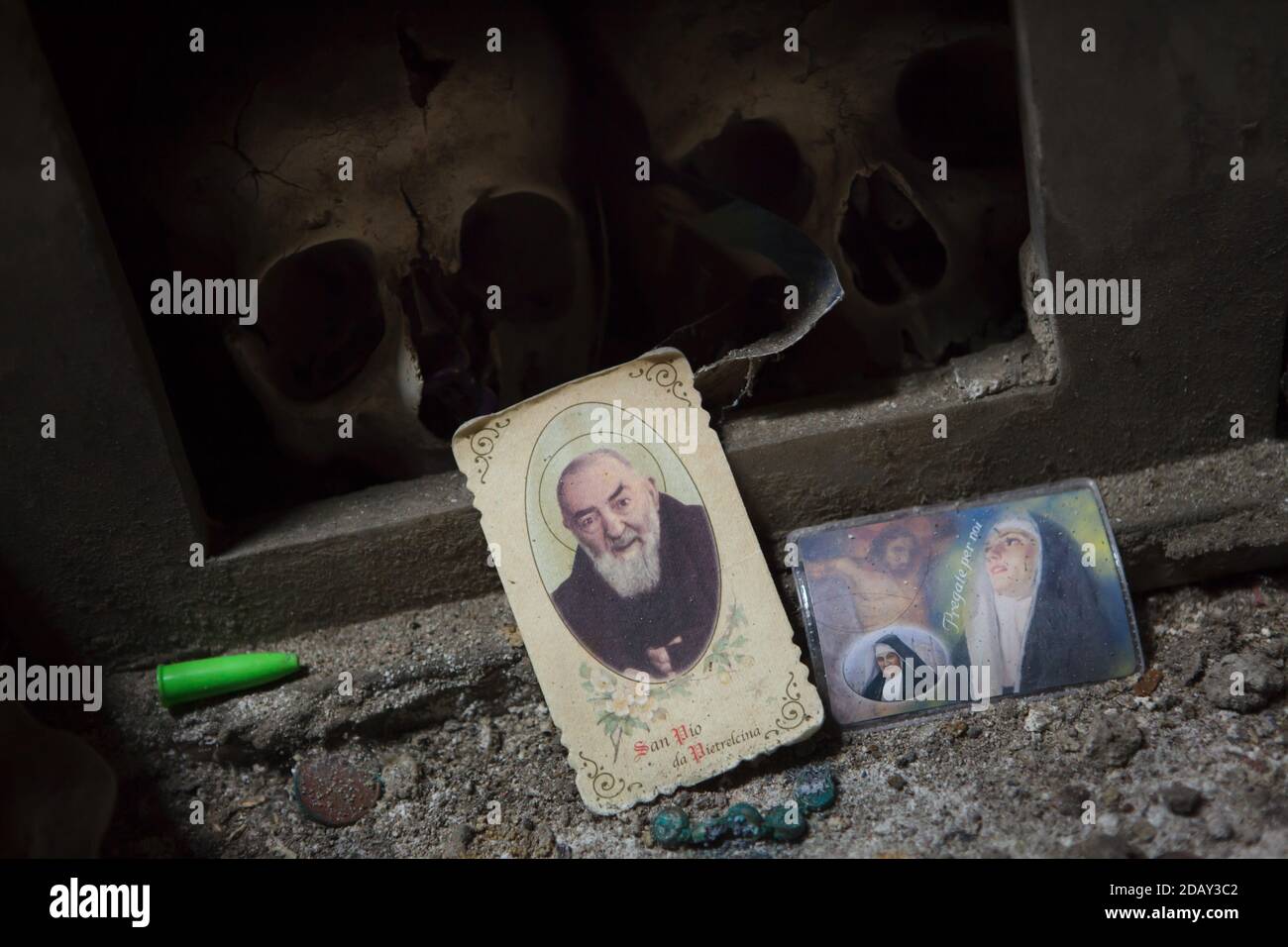 Porträt des Heiligen Pio von Pietrelcina, das neben menschlichen Schädeln auf dem Friedhof Fontanelle (Cimitero delle Fontanelle) in Neapel, Kampanien, Italien, aufgestellt wird. Das ehemalige Leichenhaus (Beinhaus) in einer Höhle im Stadtteil Materdei war der Ort, an dem sich in Neapel der spontane Kult der Hingabe an die Überreste namenlos Verstorbener entwickelte. Die Verteidiger des Kults besuchten die namenlosen Schädel im Beinhaus, um sie zu adoptieren und den Schädeln sogar Namen zu geben. Adoptierte Schädel wurden in der dekorierten Box platziert und wurden zum Gegenstand des regelmäßigen Gebets und Votivopfers. Stockfoto
