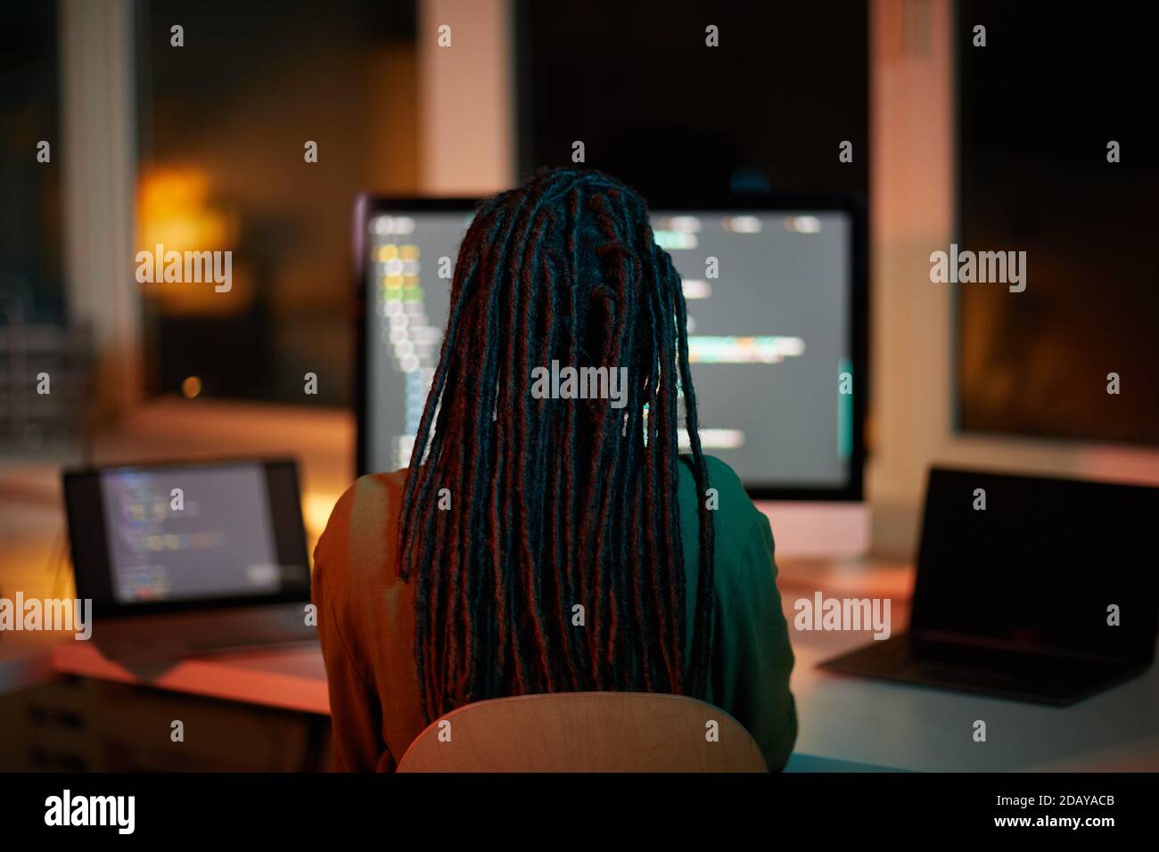 Rückansicht Porträt der weiblichen IT-Entwickler schreiben Code auf mehrere Computer-Bildschirme während der Arbeit spät in dunklen Büro, kopieren Raum Stockfoto