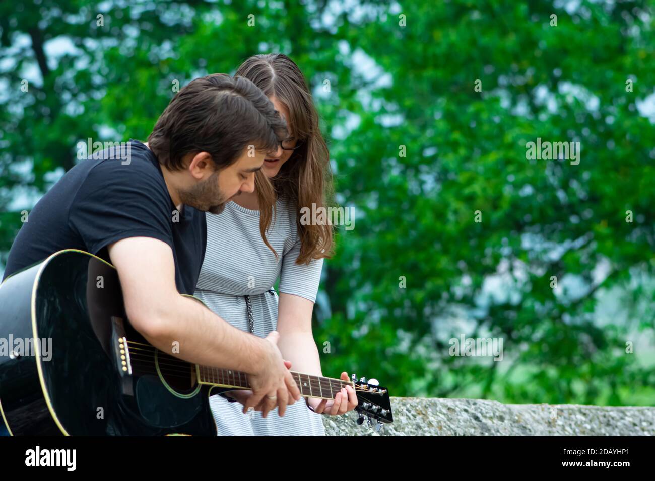 Bruder lehrt Schwester Gitarre in der Natur zu spielen Stockfoto