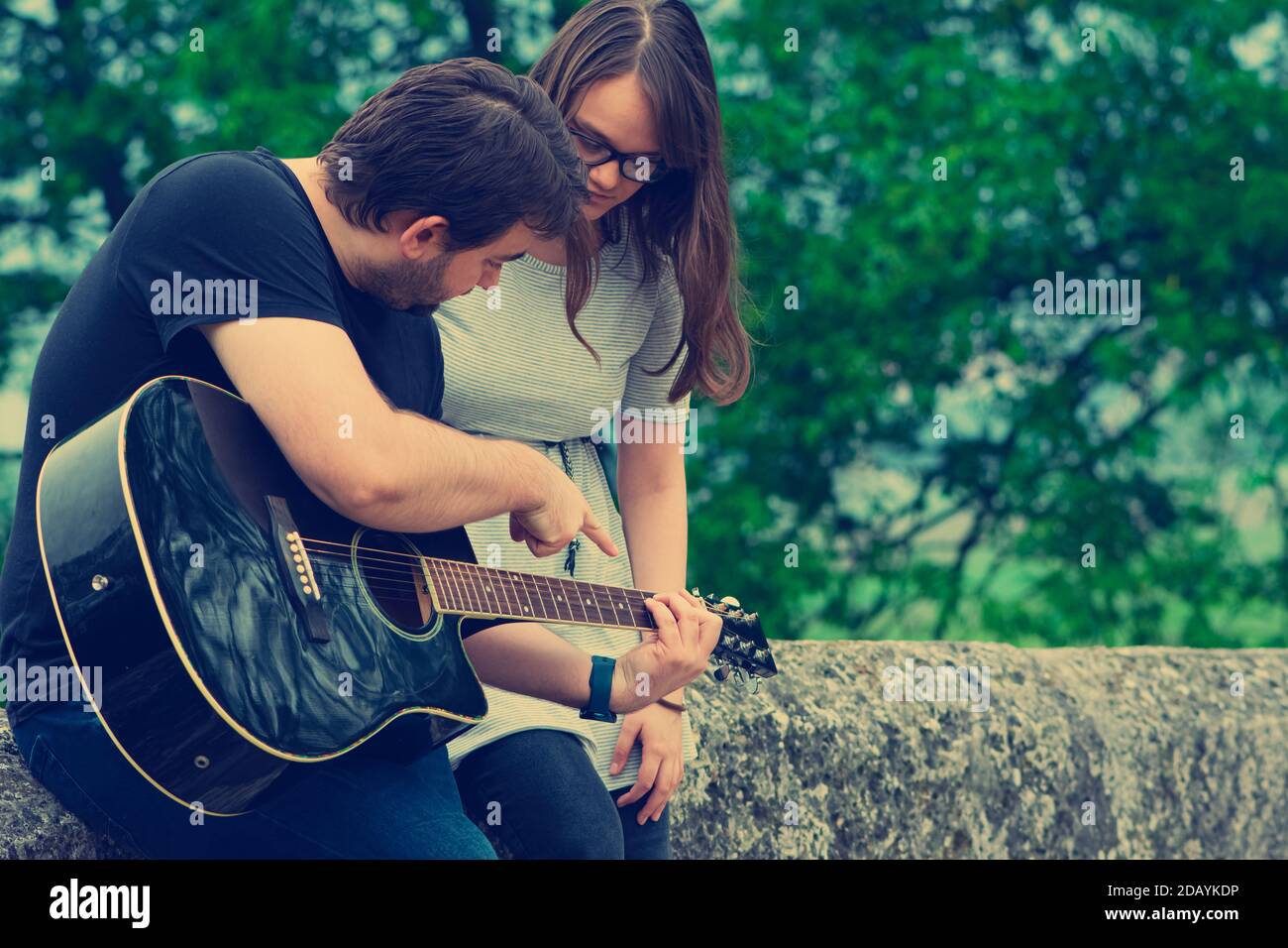 Bruder lehrt Schwester Gitarre in der Natur zu spielen Stockfoto