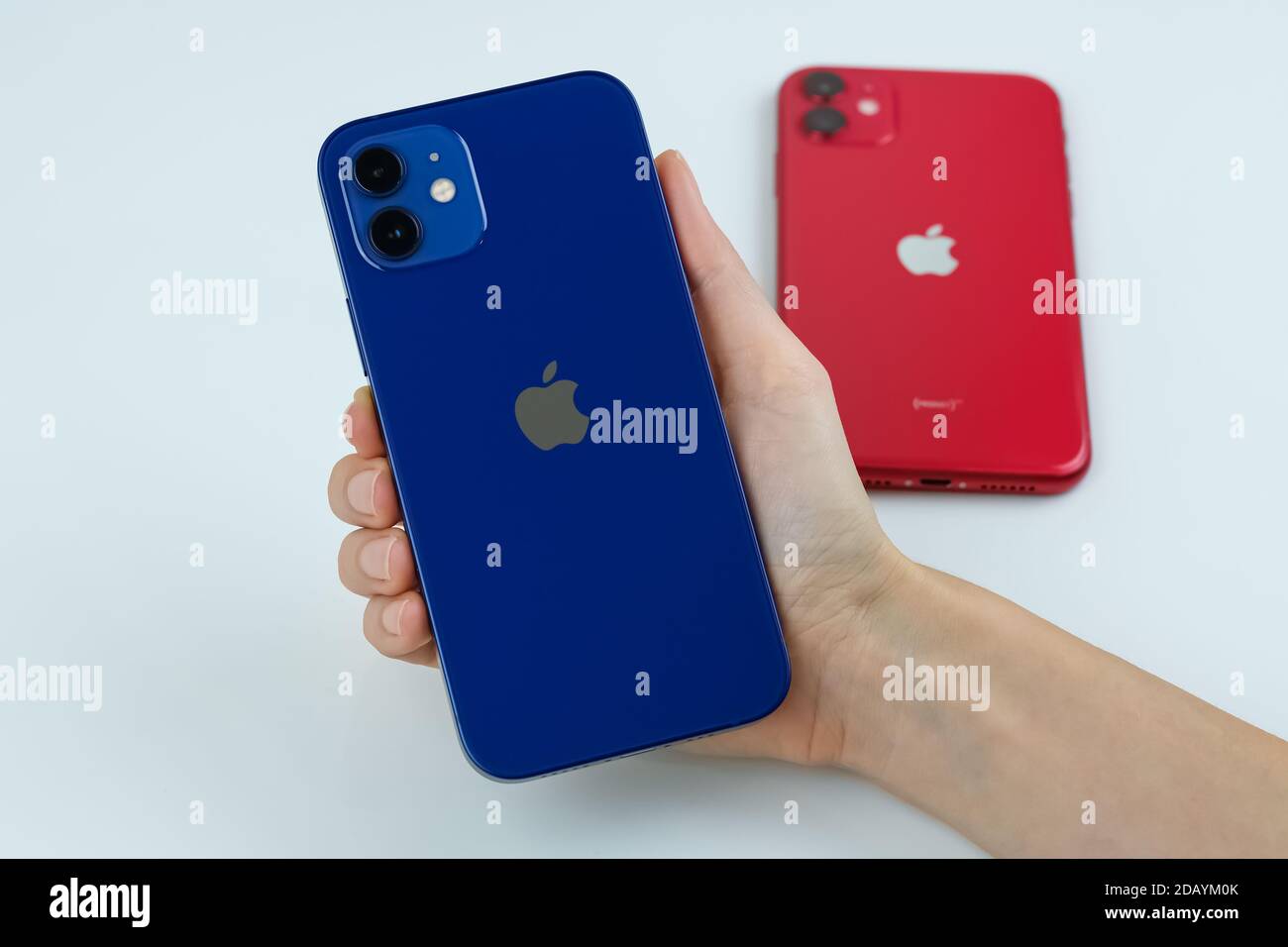 IPhone 12 in blau und iPhone 11 in rot nebeneinander. Stockfoto