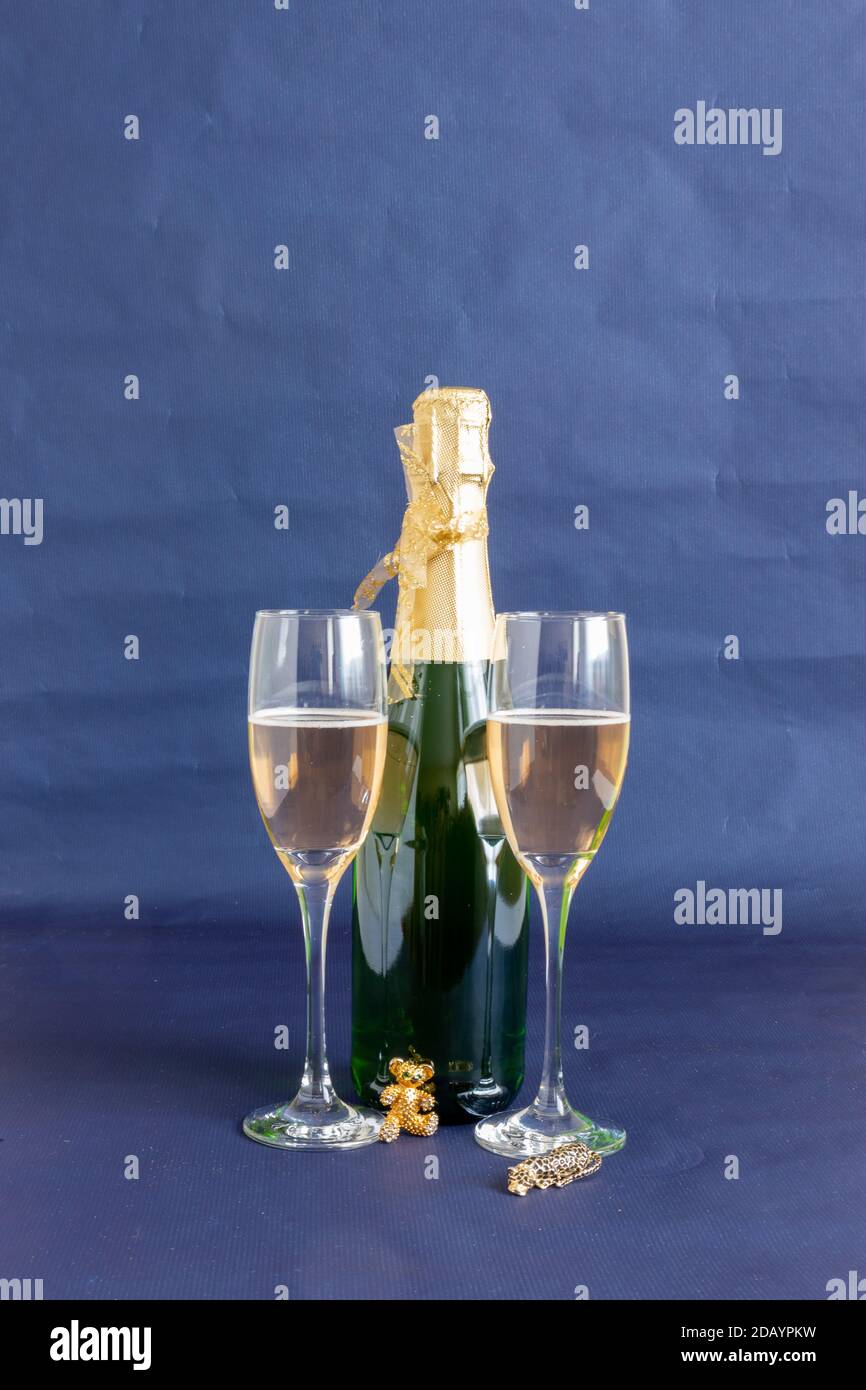 Silvesterflasche und Gläser mit goldenen Ornamenten Und Dekorationen auf blauem Hintergrund Stockfoto