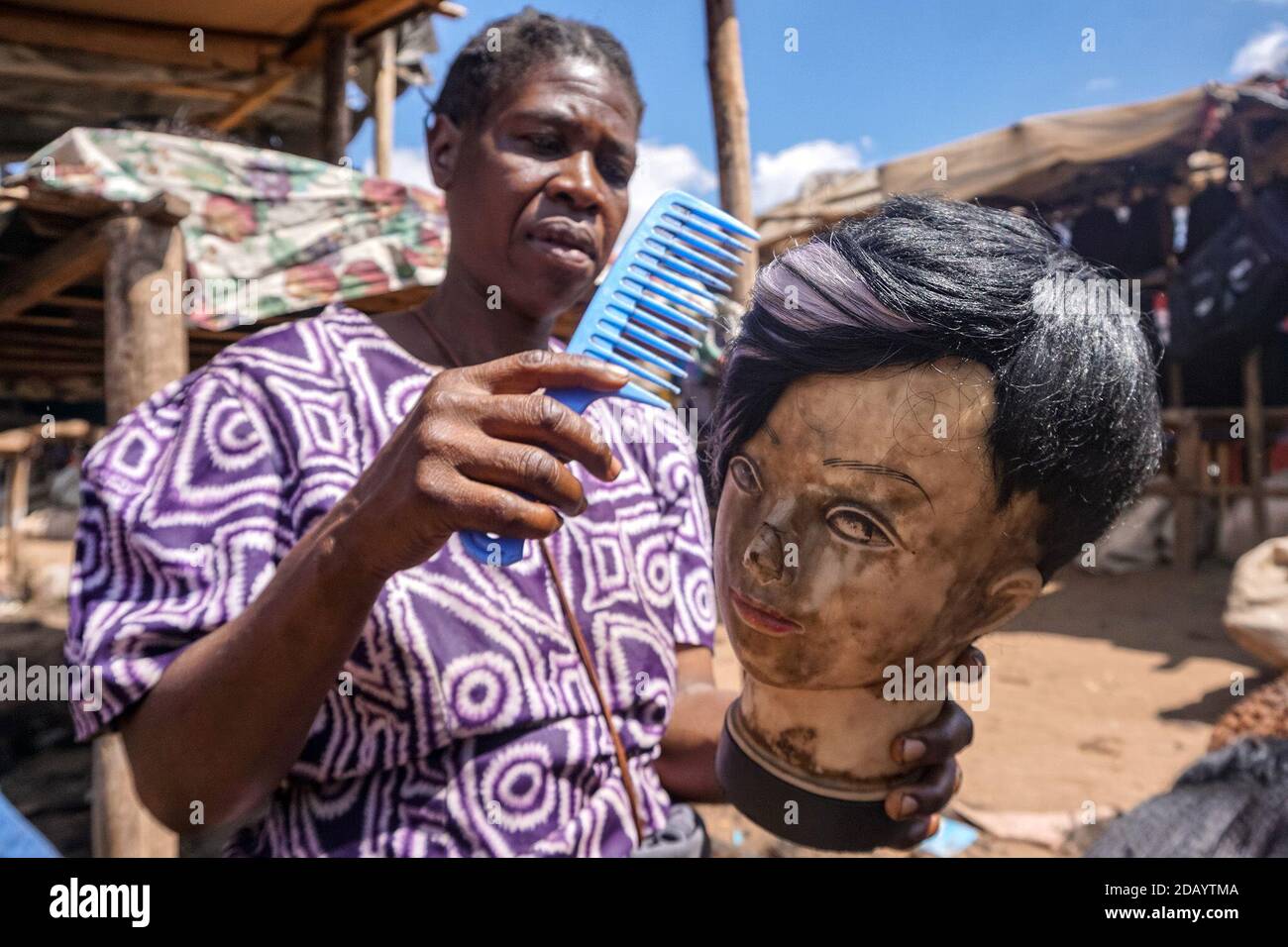 Susan Ngwari kombiniert eine ihrer Perückenkreationen an ihrer Baustelle am Straßenrand in Mbare. Stockfoto