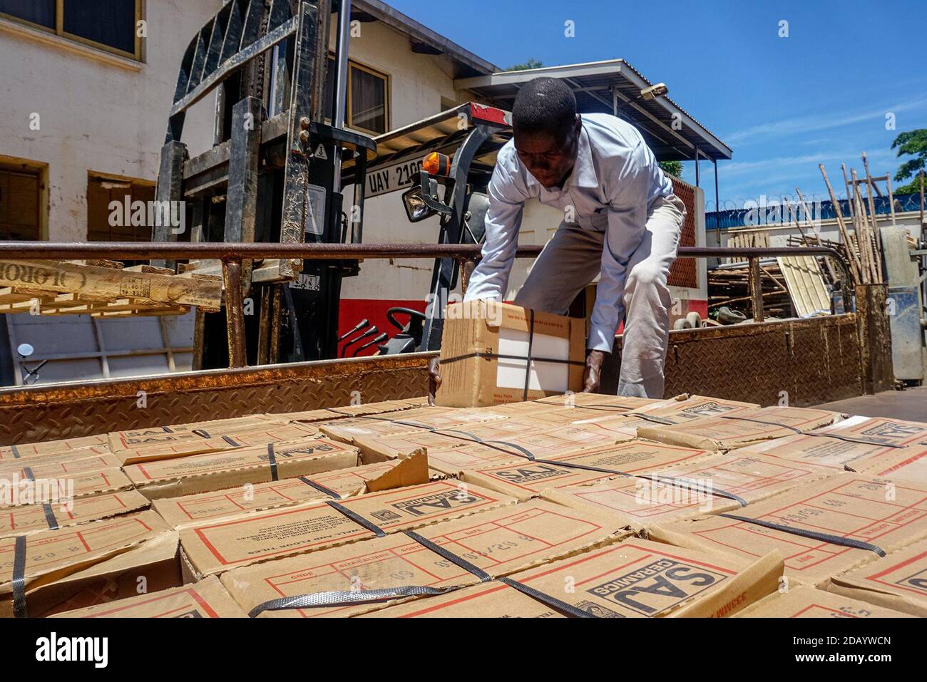Der Wena-Mitarbeiter Tom Ziburatudee lädt in Kampala, Uganda, Kisten mit Kacheln auf einen Lastwagen. Stockfoto