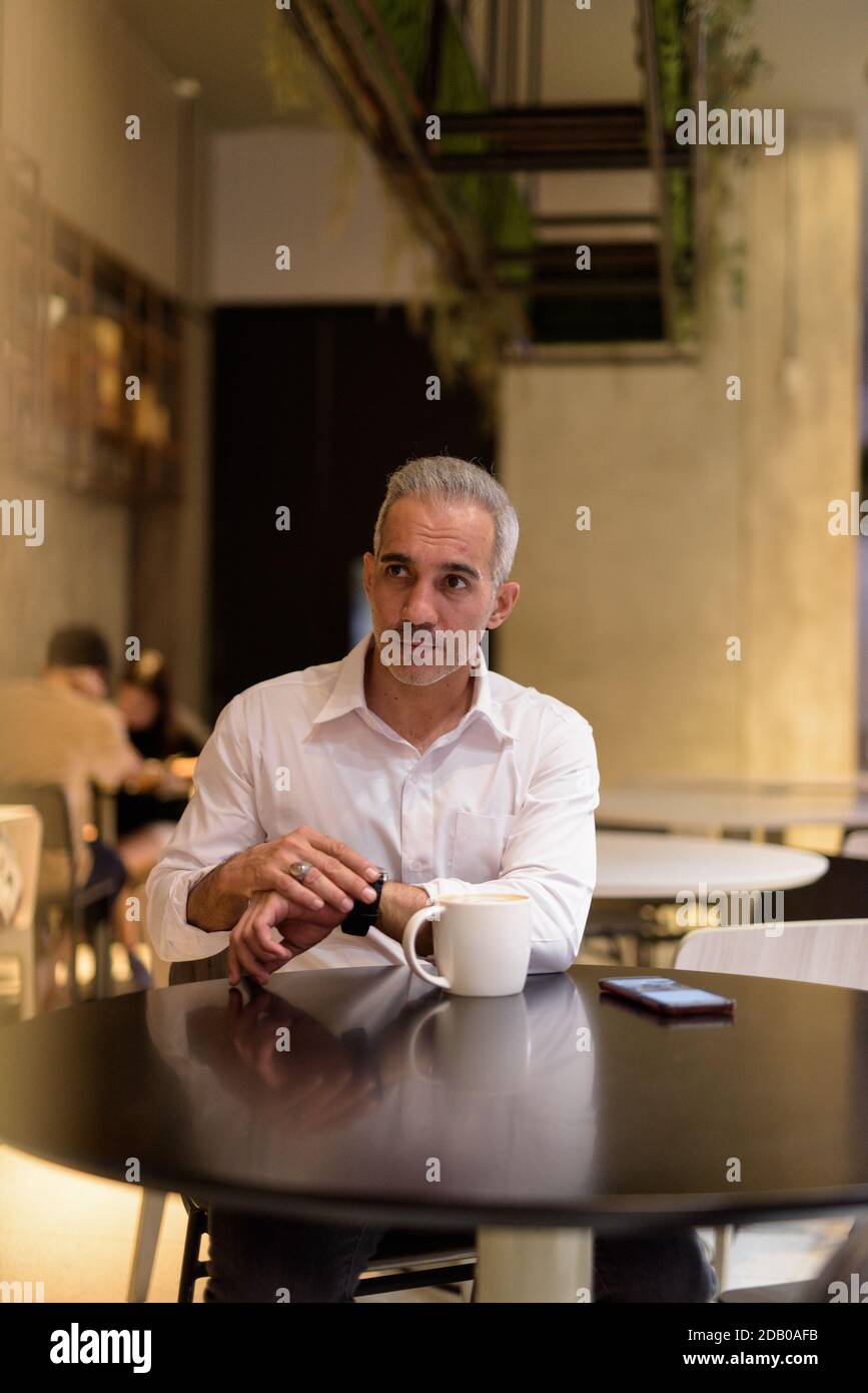 Porträt eines gutaussehenden Geschäftsmannes, der beim Denken im Café sitzt Stockfoto