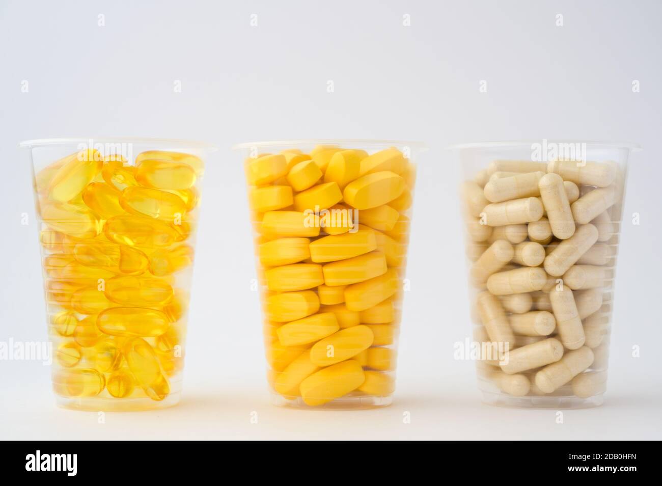 Sport diätetische Ernährung Konzept von drei Plastikbecher mit Pillen Softgels Omega3 Kapsel Vitamine Tabletten auf weißem Hintergrund mit Kopie Platz Stockfoto