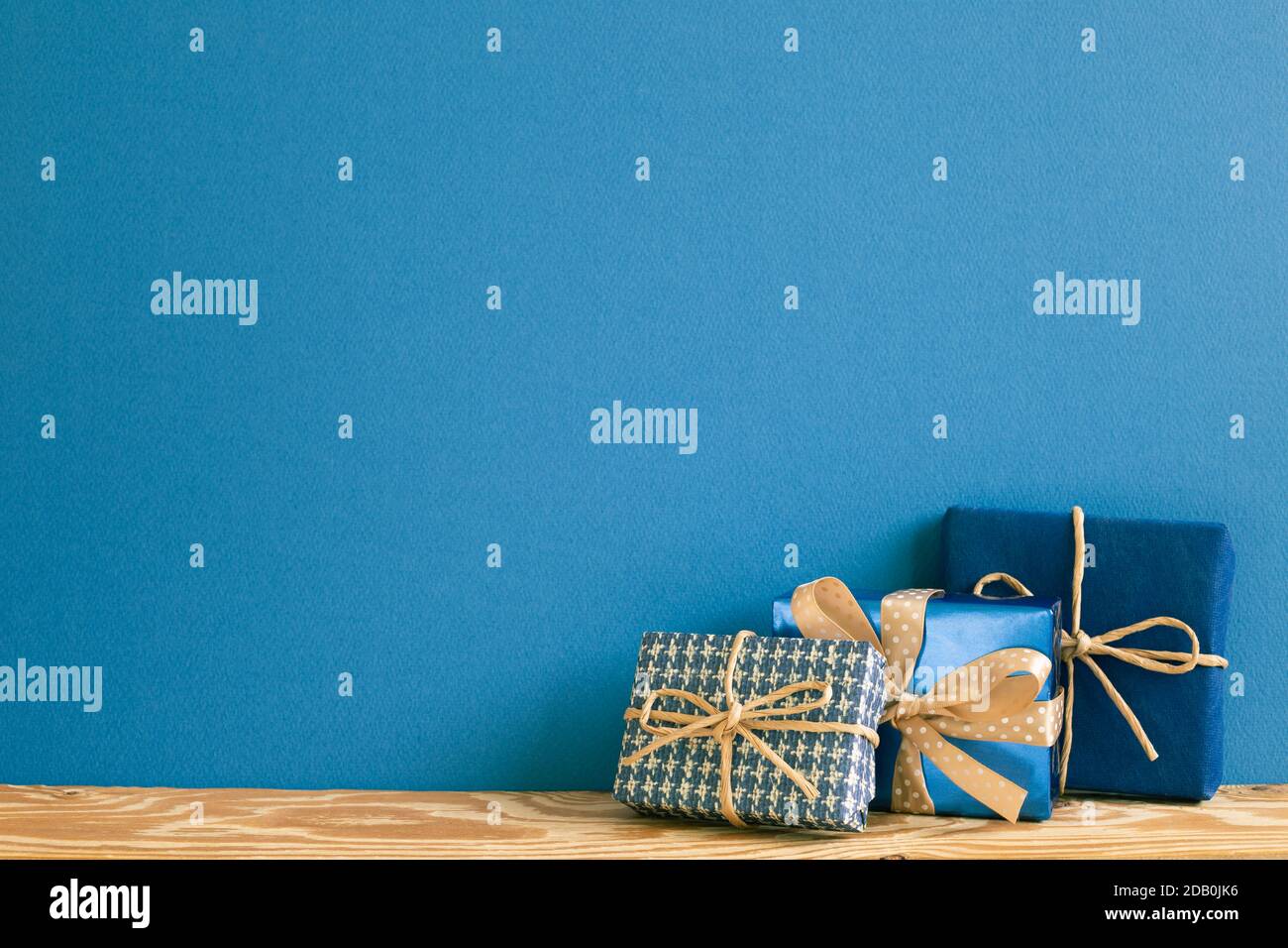 Blaue Geschenkboxen auf Holztisch mit blauem Hintergrund Stockfoto