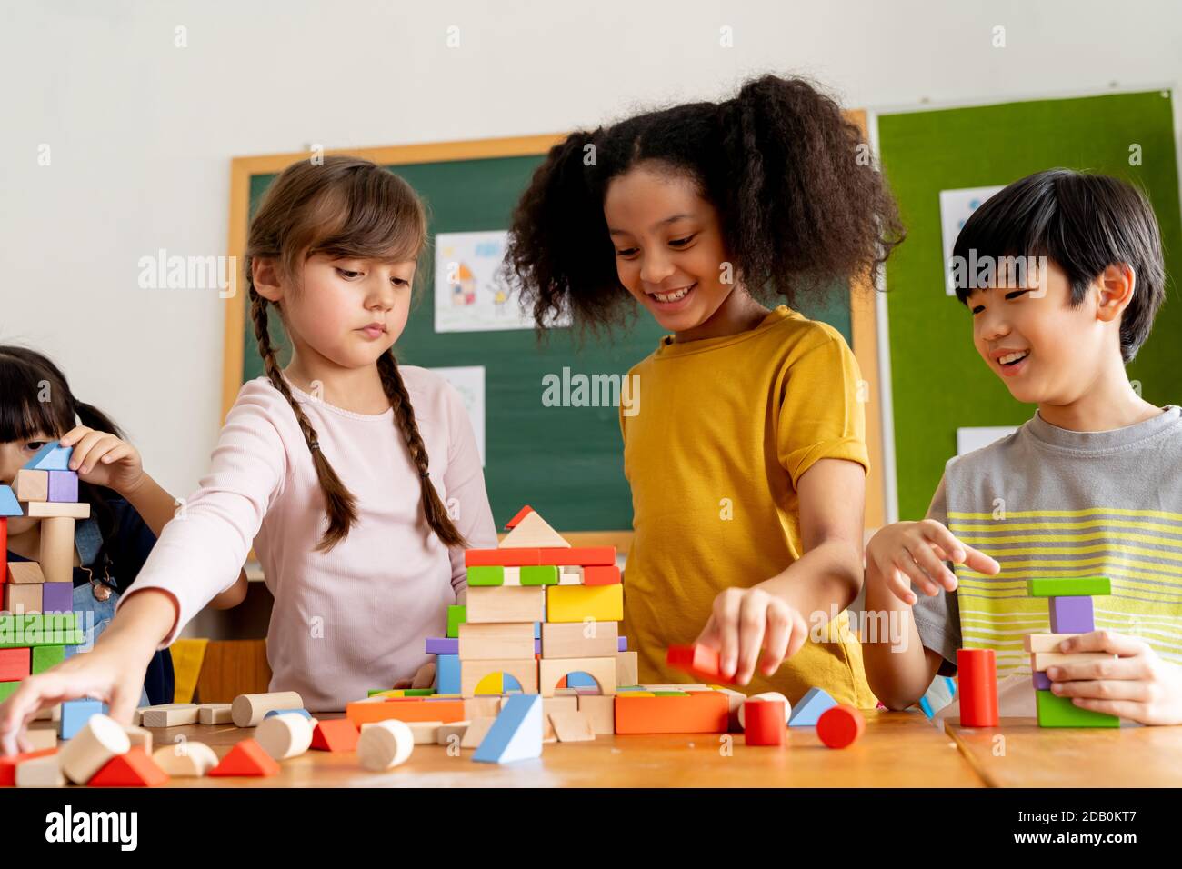 Gruppe von multiethnischen Schulfreunden mit Spielzeugblöcken im Klassenzimmer, Bildung, Lernen, Teamarbeit. Kinder spielen mit Holzblöcken im Klassenzimmer Stockfoto