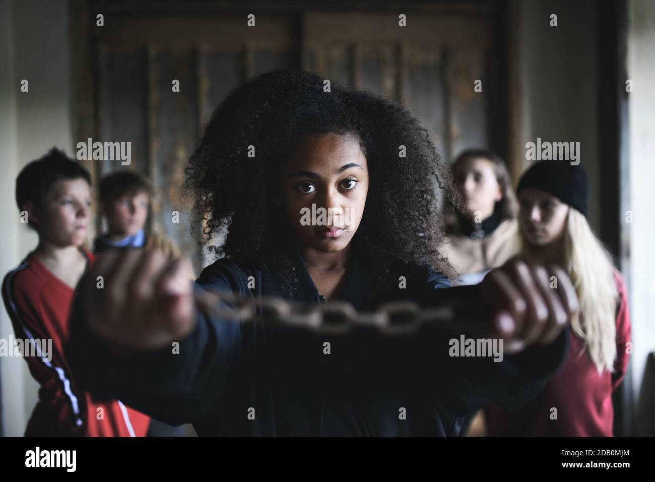 Porträt von Mixed-Race Teenager Mädchen mit Händen in Ketten drinnen in verlassenen Gebäude. Stockfoto