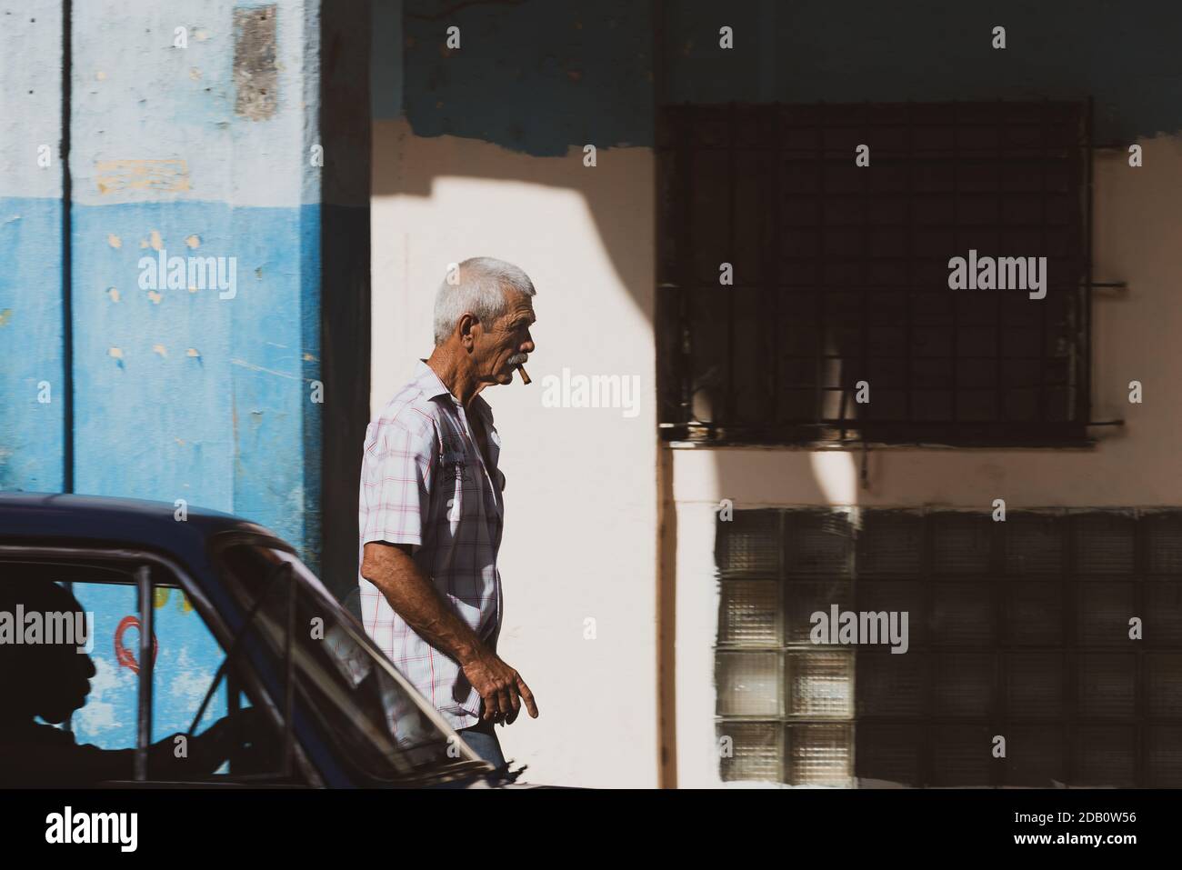 Mann mit Zigarre läuft im Zentrum von Havanna. Kubanische Straßenszene. Stockfoto