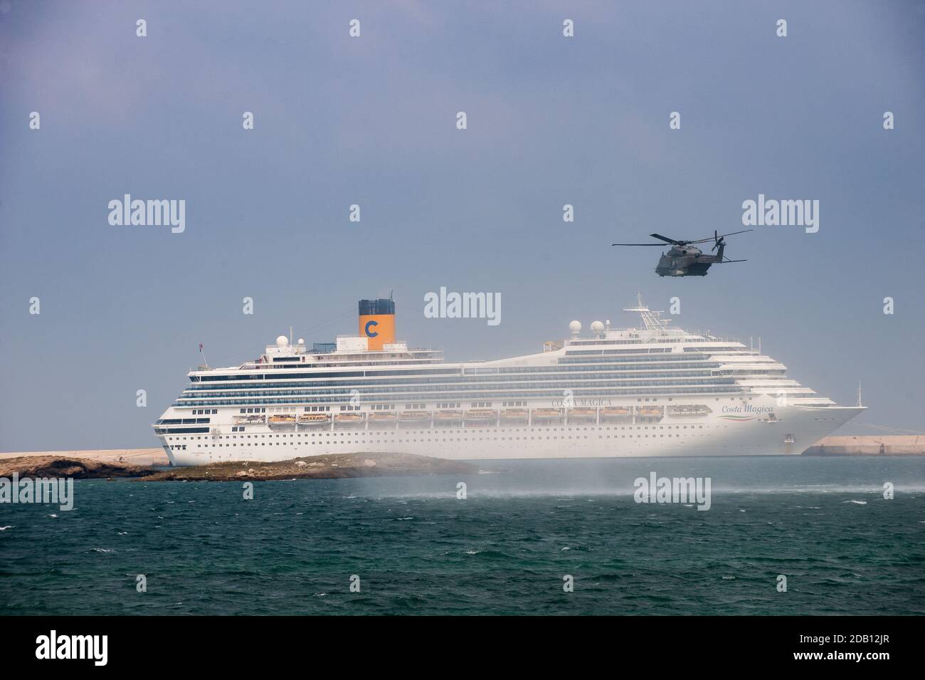 Der italienische Marine-Hubschrauber NH-90 führt eine Bohrmaschine im Hafen von Brindisi durch. Im Hintergrund lag das Kreuzfahrtschiff 'Costa Magica' aufgrund des Anhaltes in cr vor Anker Stockfoto