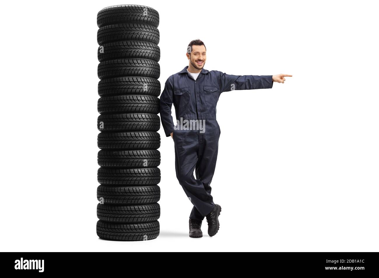 In voller Länge Porträt eines Auto-Mechaniker lehnt sich an ein Haufen von Autoreifen und zeigt auf die Seite isoliert Auf weißem Hintergrund Stockfoto