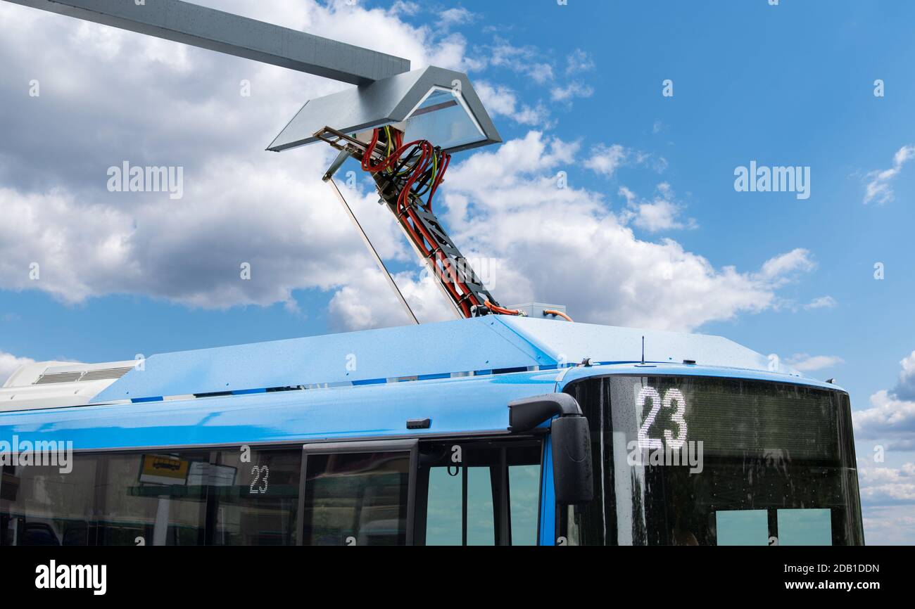 Elektrobus an einer Haltestelle wird von Pantograph geladen Stockfoto