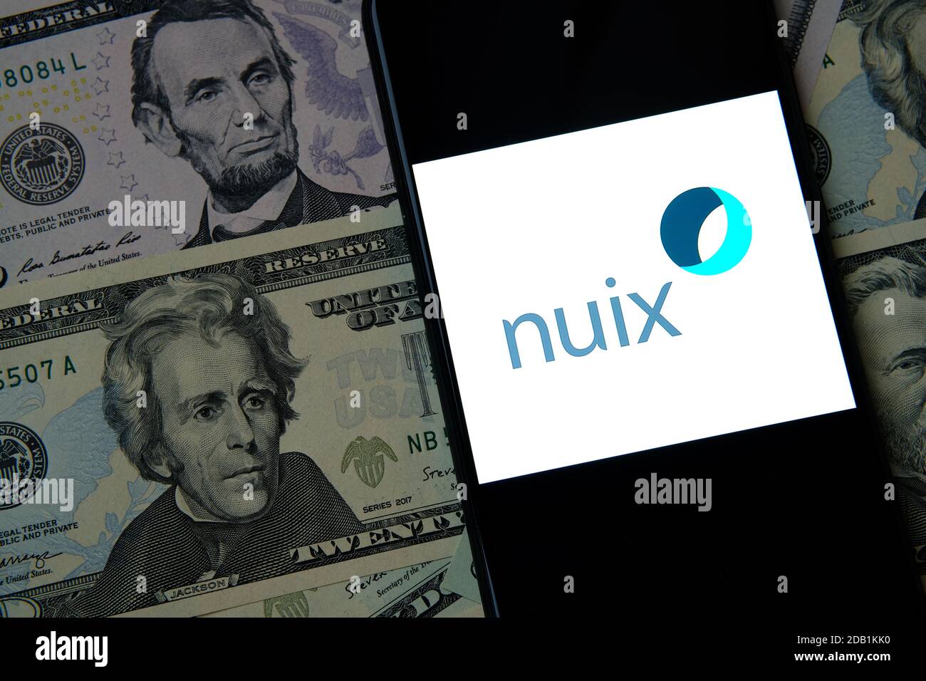NUIX Logo auf dem Smartphone, das auf US-Dollar-Scheinen platziert wird Stockfoto