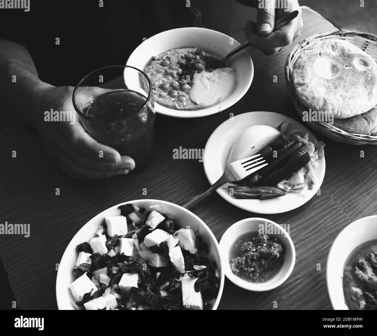 Arbeiter Mittagspause in einfachen Diner. Mann isst frischen warmen Hummus mit Pita Brot, Gurken, Feta-Käse-Salat und trinken frischen Saft. Gesunde Ernährung. Stockfoto