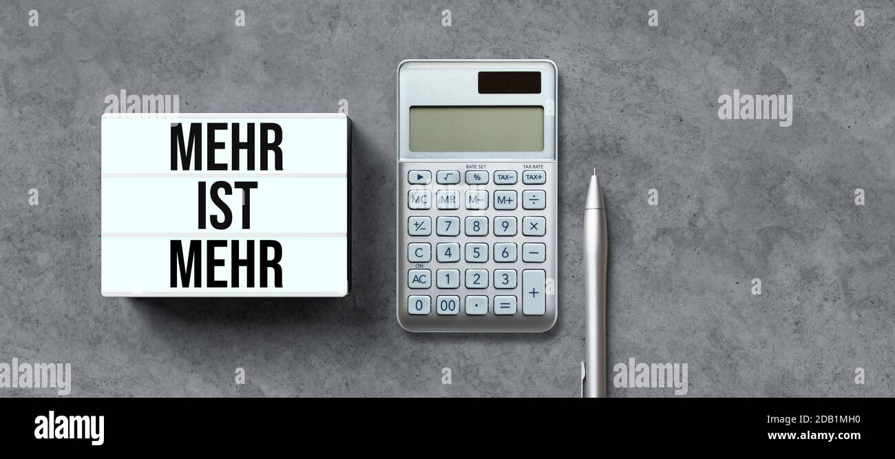 lightbox mit deutscher Botschaft für MEHR IST MEHR und Rechner Auf konkretem Hintergrund Stockfoto