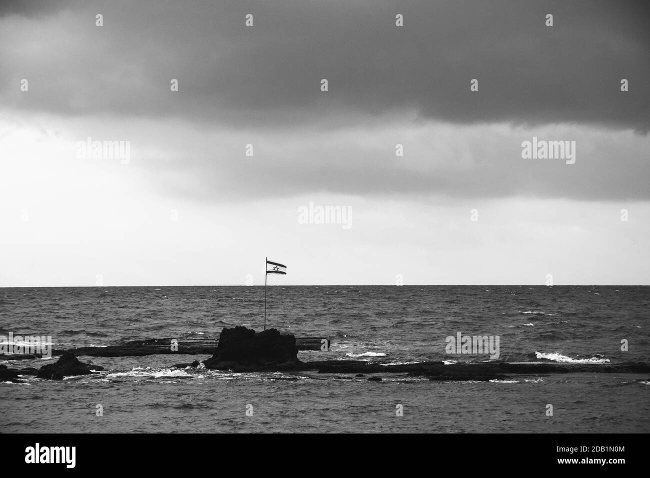 Flagge Israels auf den Felsen im Meer nahe der Küste von Tel Aviv. Israelische Geschichte, Kultur, Politik, Unabhängigkeitstag Feier, Identitätskonzepte. Stockfoto