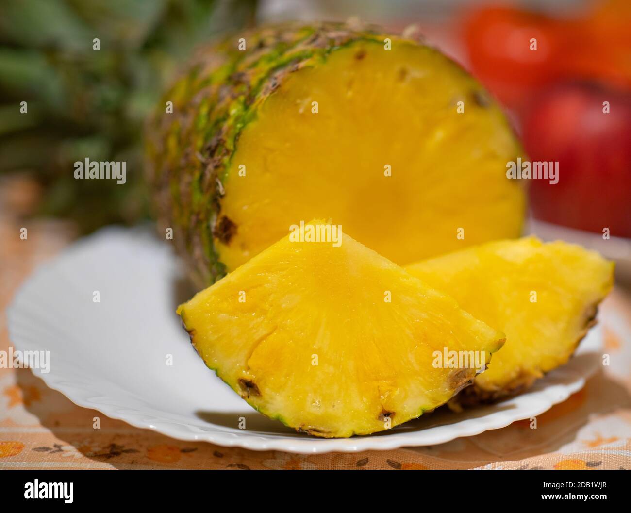 Ananasfrüchte auf einem weißen Teller und rote Äpfel hinein Der Hintergrund Stockfoto