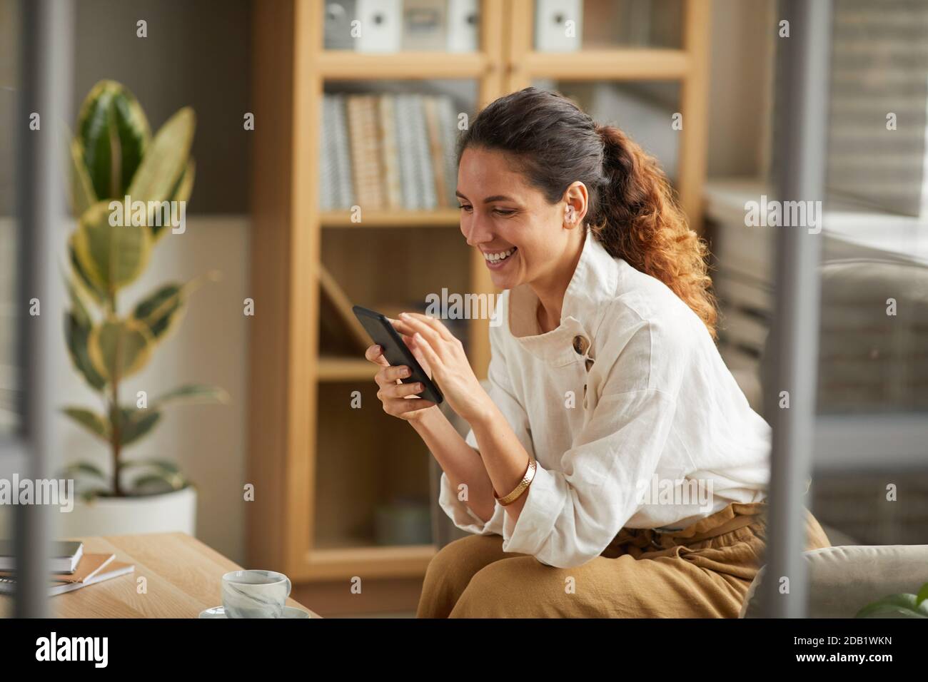 Porträt einer eleganten erwachsenen Frau, die auf den Smartphone-Bildschirm schaut und lacht, während sie online mit Freunden und Familie chattet, Platz kopieren Stockfoto
