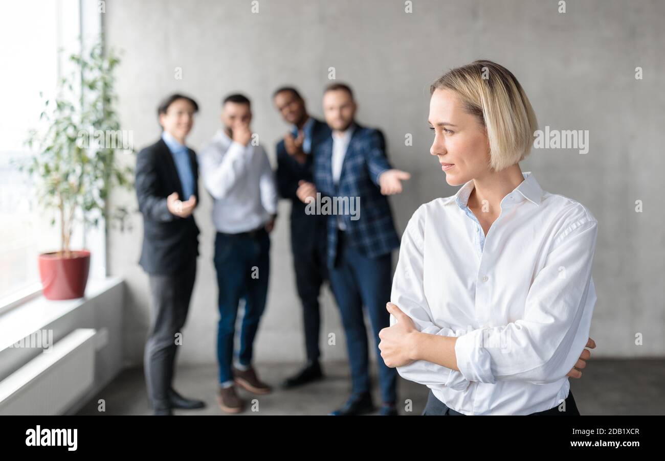 Männliche Mitarbeiter Flüstern Hinter Unglücklich Opfer Geschäft Dame Im Büro Stockfoto