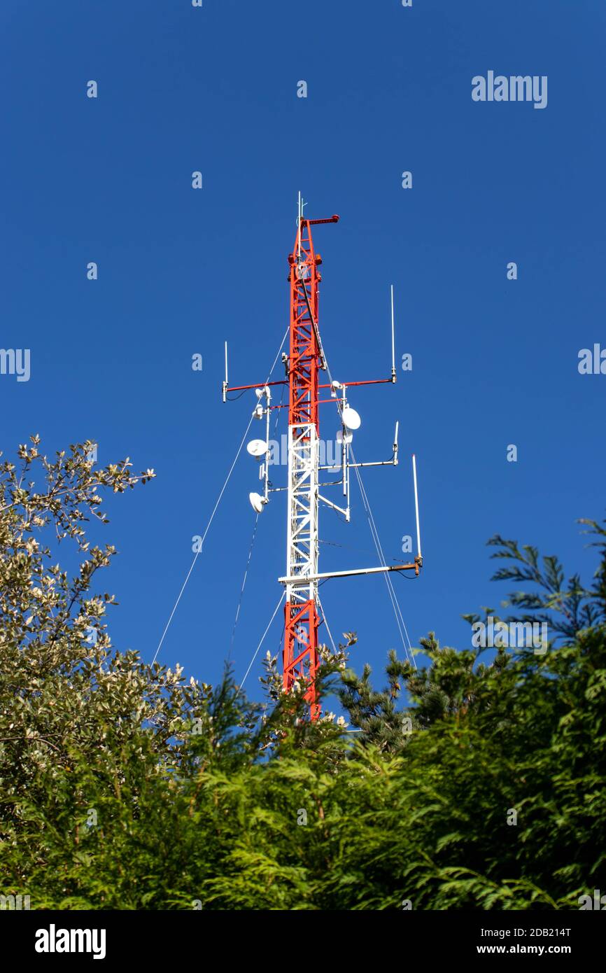 Rot-weißer Telekommunikationsmast oder mobiler Turm mit Satellit Antennen Stockfoto