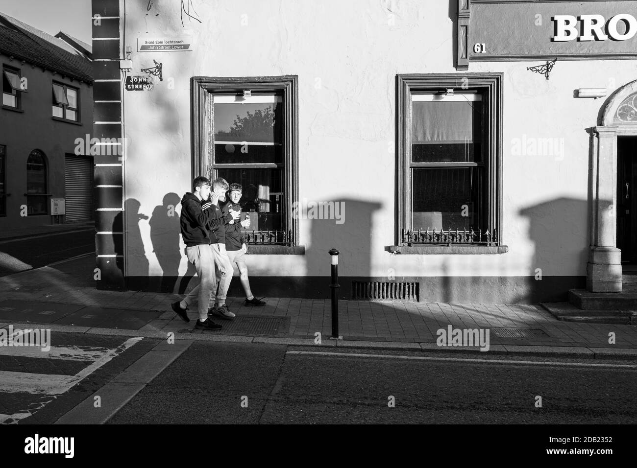 Drei Teenager-Jungen trinken und plaudern, während sie auf der John Street vor dem Brogans öffentlichen Haus in Kilkenny, County Kilkenny, Irland, gehen Stockfoto