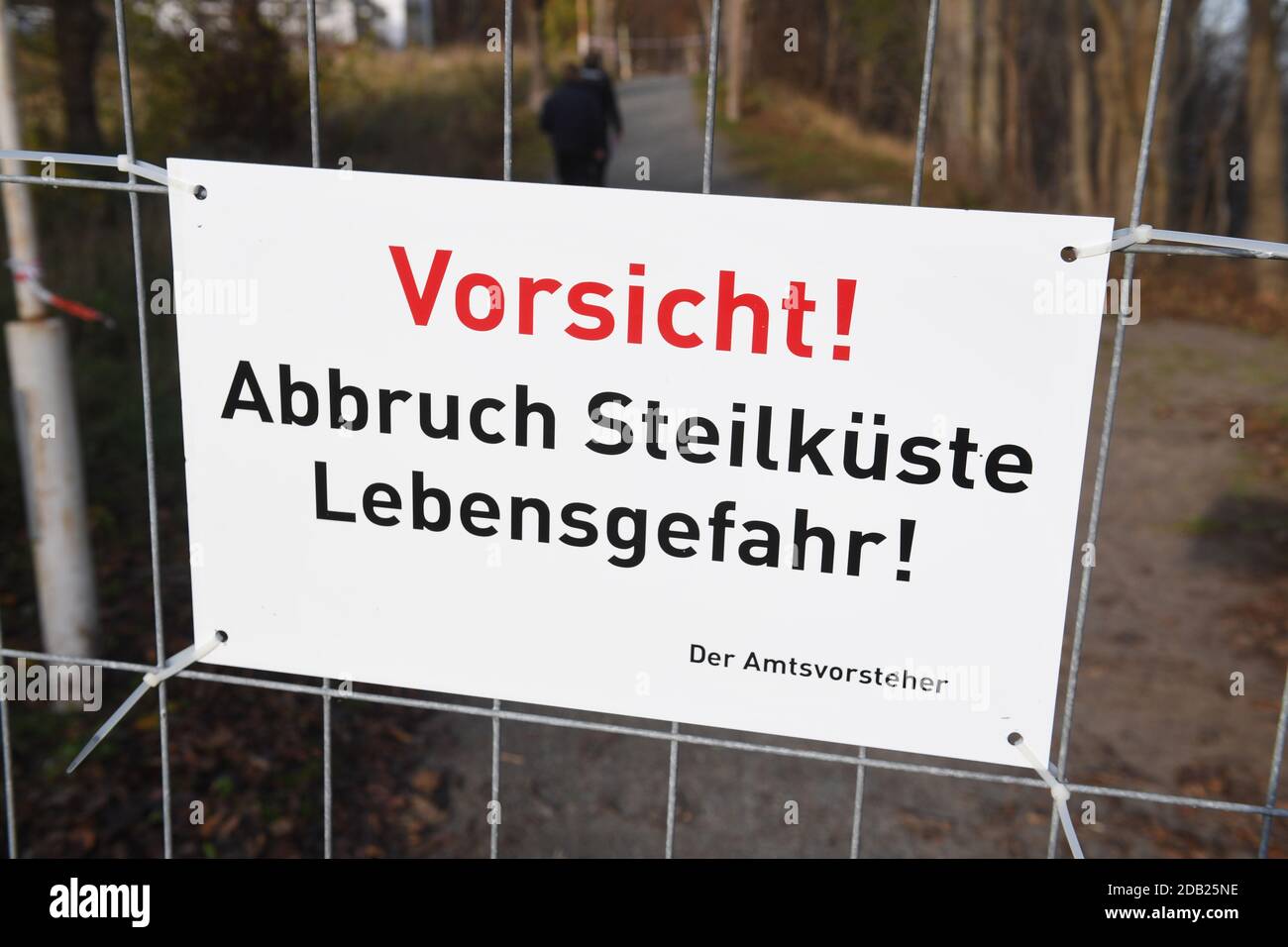 Stralsund, Deutschland. November 2020. Ein Schild mit den Worten 'Vorsicht! Abbruch steile Küste Gefahr für das Leben' hängt an einem Zaun. In der Nähe des Piers rutschte am 14.11.2020 ein großer Bereich des Abhangs ab. Nach Angaben der Gemeinde war dies eine Fläche von etwa 150 Quadratmetern. Erde und Bäume stürzten etwa 300 Meter nördlich des Piers ab und vergruben das Ende eines Strandweges. Quelle: Stefan Sauer/dpa-Zentralbild/dpa/Alamy Live News Stockfoto