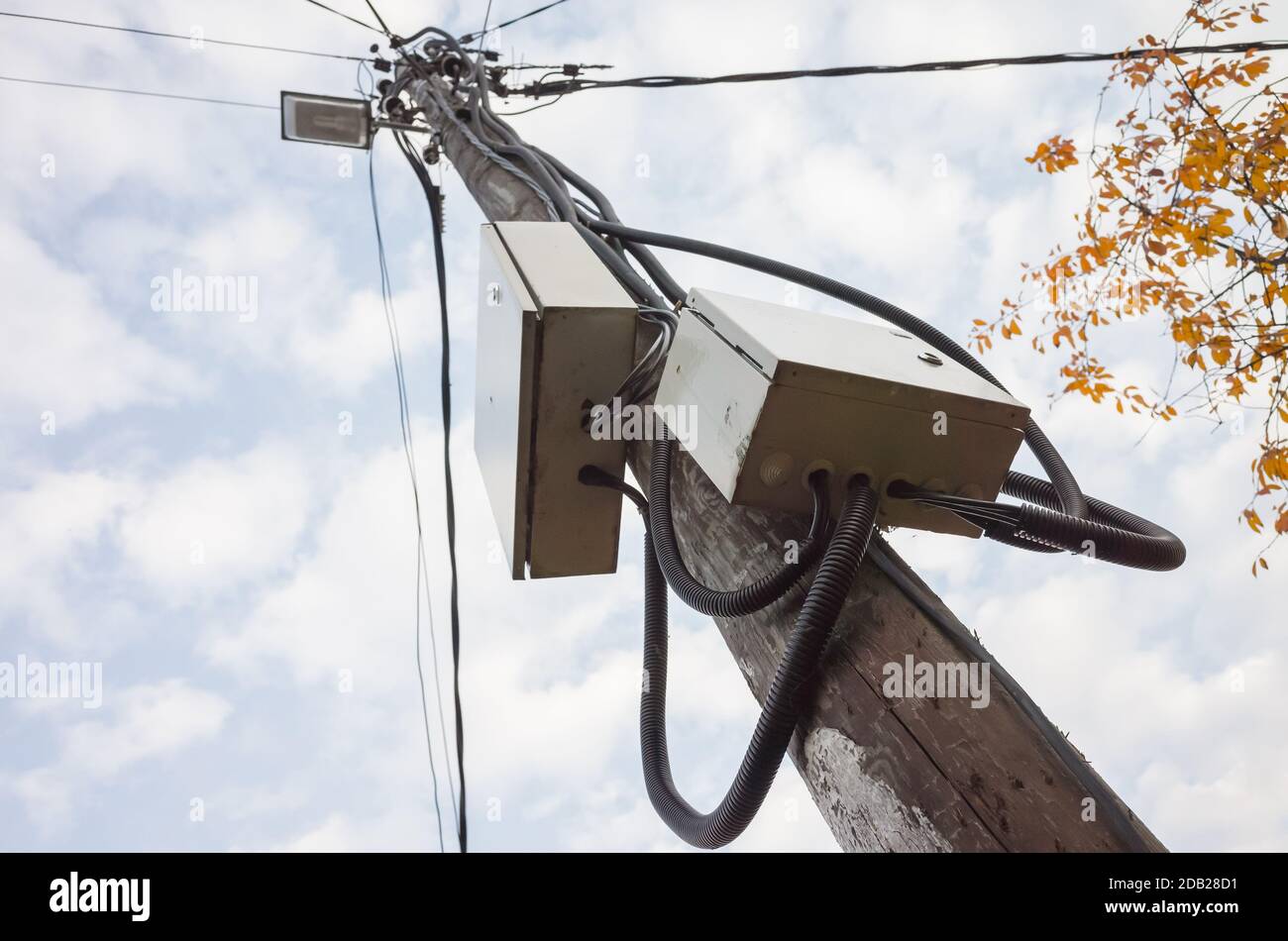 Strommast mit Straßenlicht, elektrischen Verteilerkästen und Drähten ist unter bewölktem Himmel am Tag Stockfoto