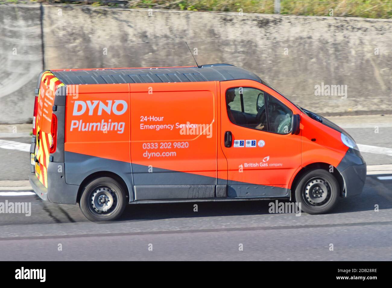 Seitenansicht des Fahrers von Dyno Plumbing van A British Gas Firma Geschäft Werbung 24 Stunden Notfall Klempner im Fahrzeug Fahren Sie auf der britischen Autobahn Stockfoto
