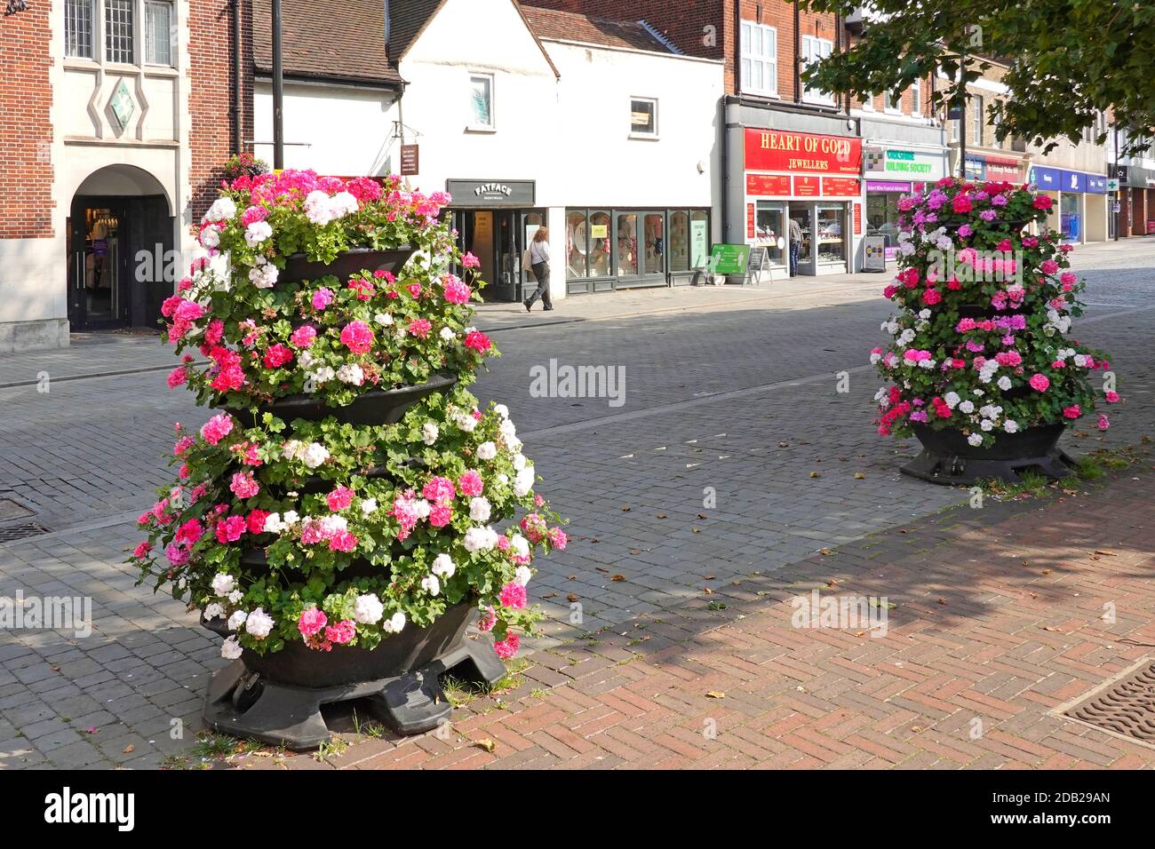 Eine einsame Frau Shopper Spaziergang entlang Bürgersteig verlassen Brentwood Shopping High Street in Covid 19 Coronavirus Pandemie Blumenanzeige Essex England GB Stockfoto