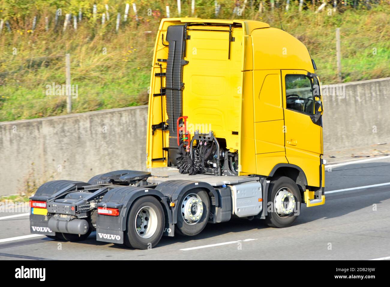 Zurück & Seitenansicht Kabine von gelb sauber Volvo solo Sattelzugmaschine mit Doppelrückachse und Hauptfahrwerk Mit einer Achse angehoben & Auspuff auf UK Autobahn Stockfoto