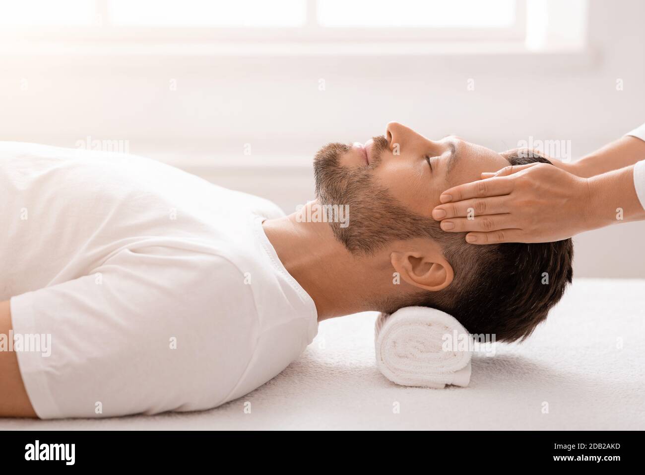 Bärtiger Mann genießt eine entspannende Kopfmassage im Spa Stockfoto