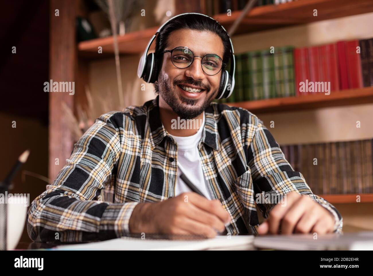 Portrait Von Happy Indian Student Sitzt Am Schreibtisch In Der Bibliothek Stockfoto