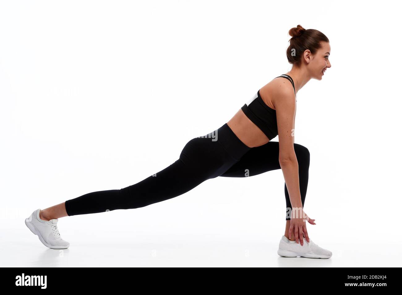 Schlanke und starke kaukasische Frau tun Stretching-Übung vor dem körperlichen Training, weiß isoliert Hintergrund Stockfoto