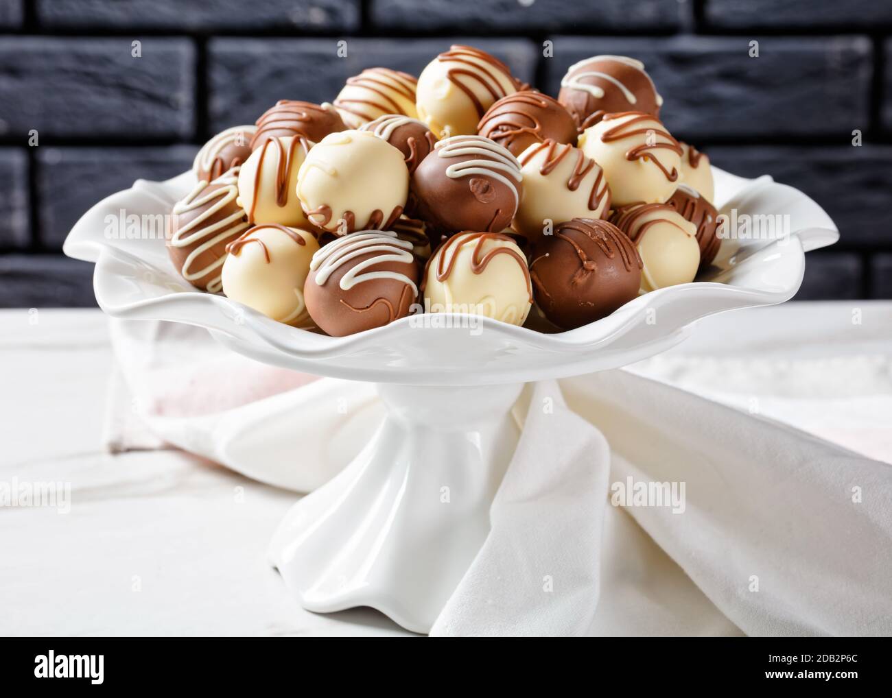 Schokoladentrüffelkugeln auf einer Platte auf einem Marmortisch Stockfoto