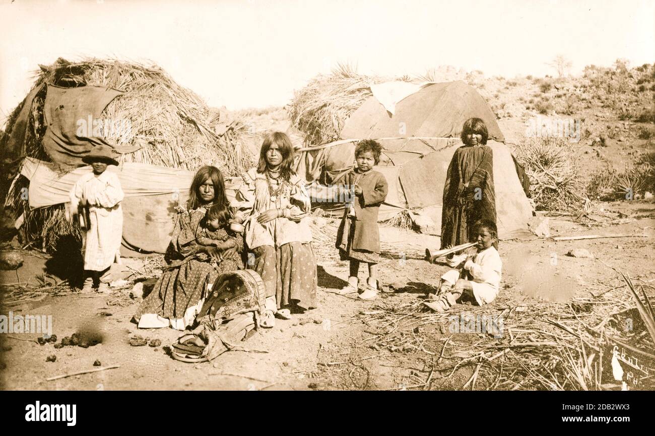 Eine Gruppe von Apache-Indianern vor ihren reetgedeckten Hütten. Stockfoto