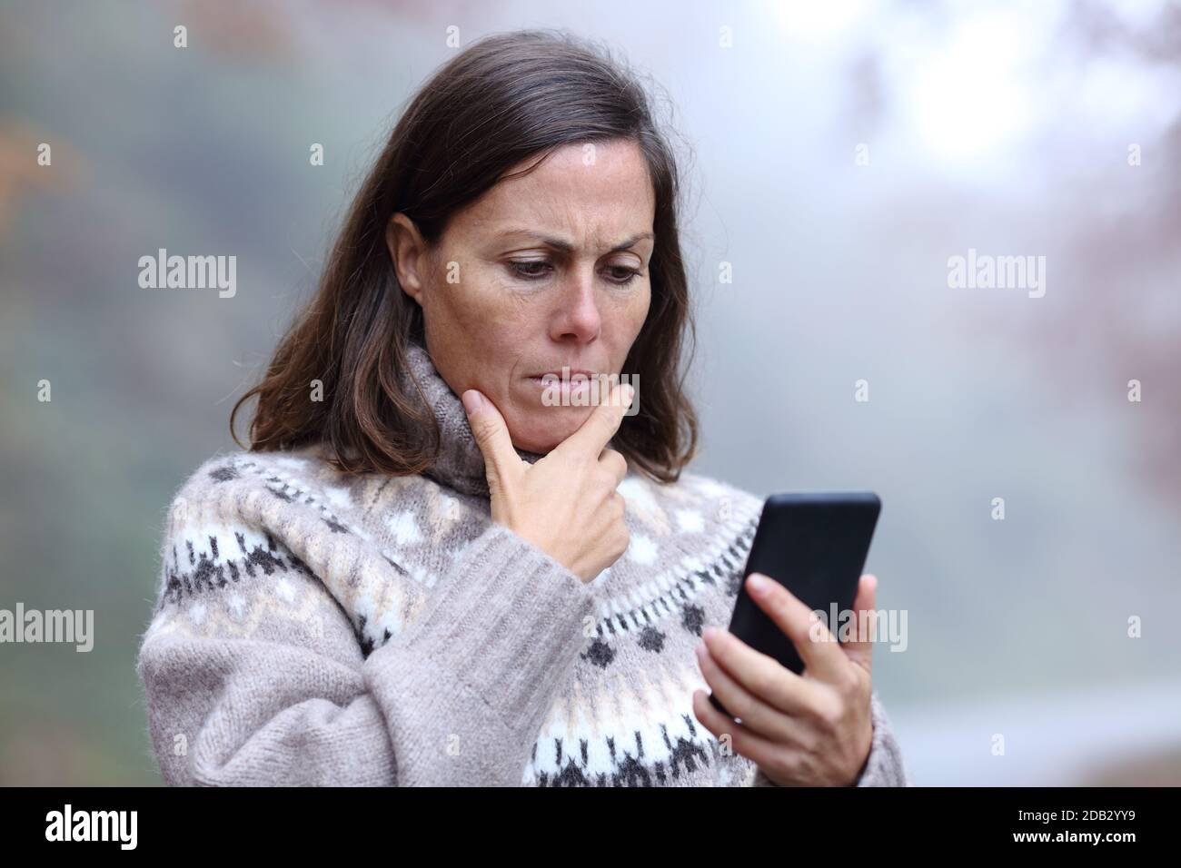 Besorgt mittleren Alters Frau lesen Smartphone-Nachricht im Herbst Saison Stockfoto