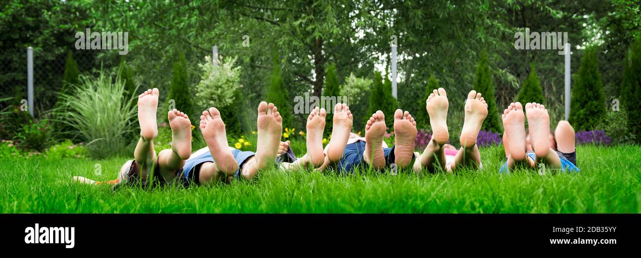 Familie entspannt sich auf grünem Gras, barfuß hinlegen und in den Himmel blicken Stockfoto