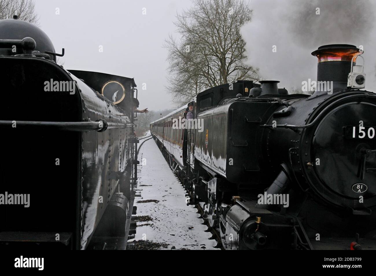 Zugfahrer winken, während sie sich auf der schneebedeckten Severn Valley Railway, Shropshire, vorbeifahren Stockfoto