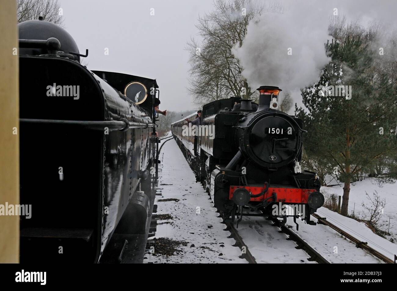 Zugfahrer winken, während sie sich auf der schneebedeckten Severn Valley Railway, Shropshire, vorbeifahren Stockfoto